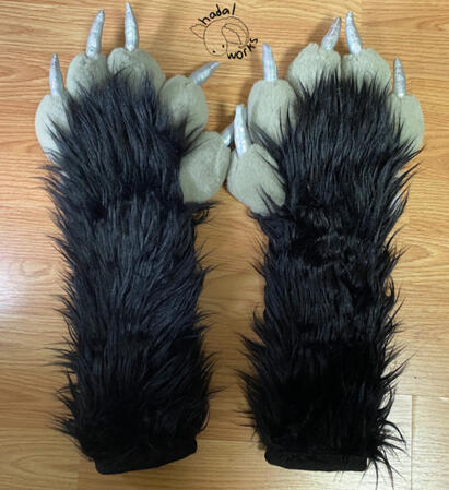 A pair of fursuit paws with long arm sleeves. The arms are black, the toes are gray, and the claws are holographic silver.