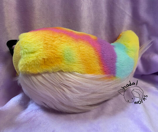 Small stumpy fursuit tail with pastel tie-dye fur and a pink underfur.